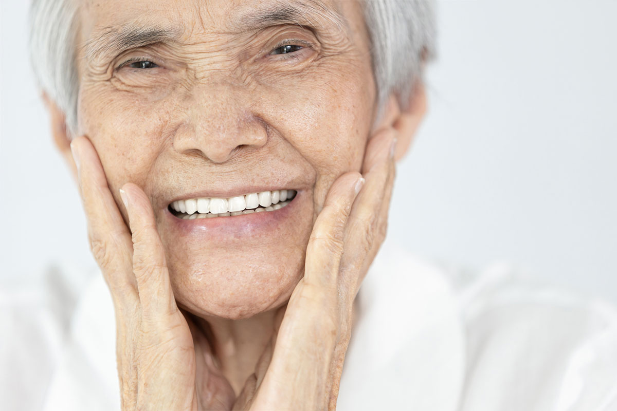 An elderly lady expressing joy over her partial dentures by Battlefords