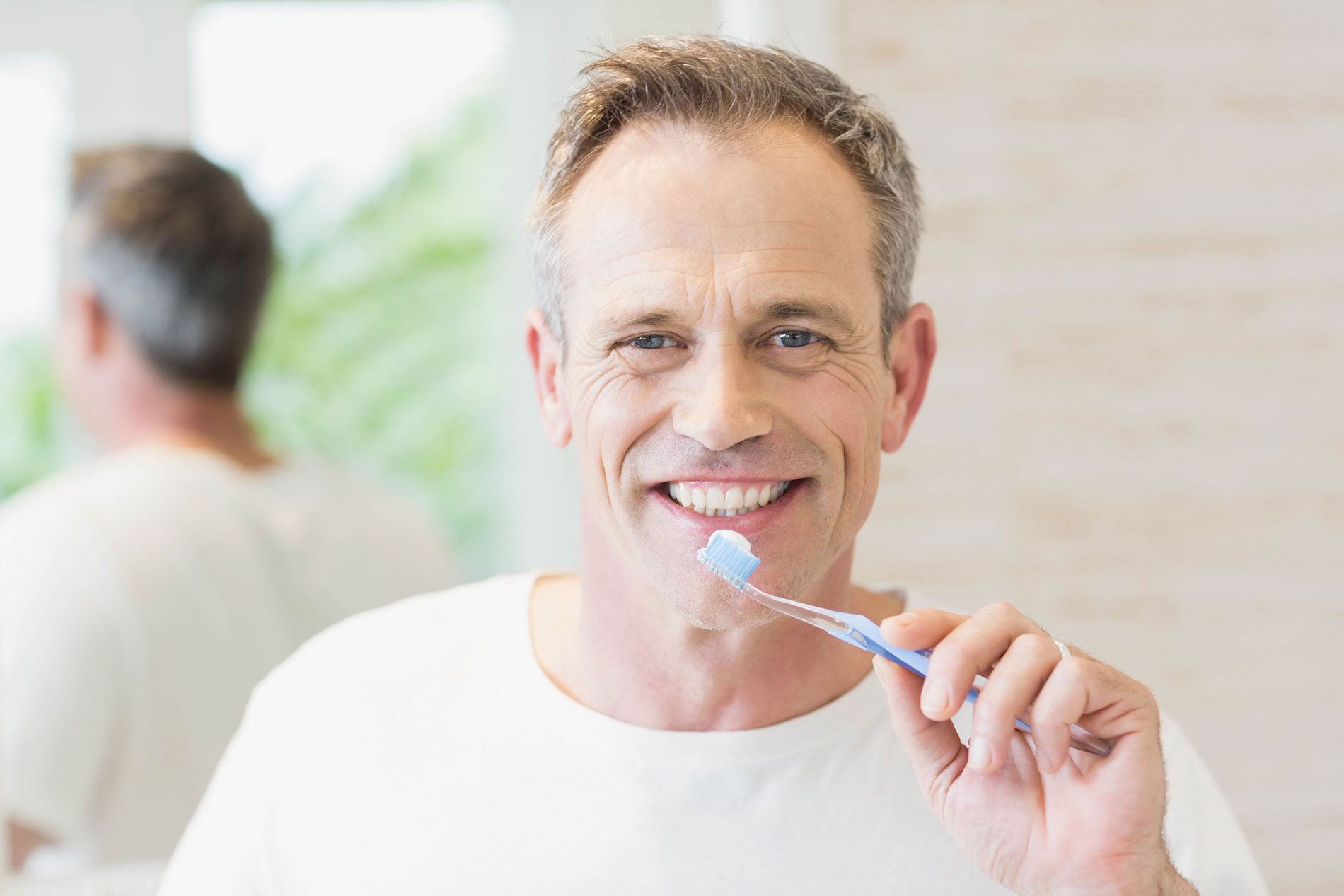 A man practicing denture cleaning with his toothbrush