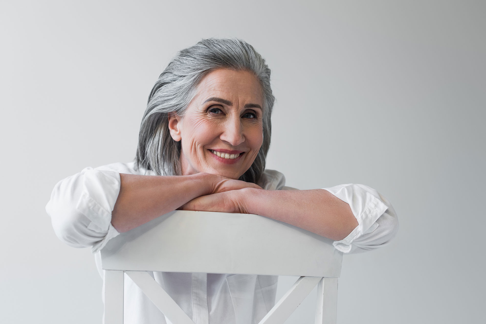 A lady leaning on a chair wearing her new dentures on implants